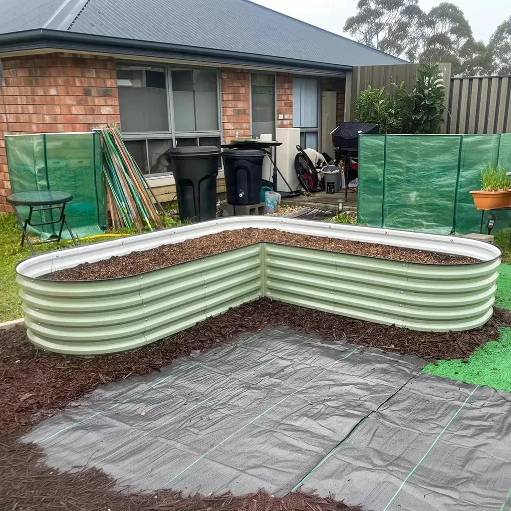 Vegega L-shaped knee-high raised garden bed freshly assembled in a backyard, showing the corner-fitting L-shape design